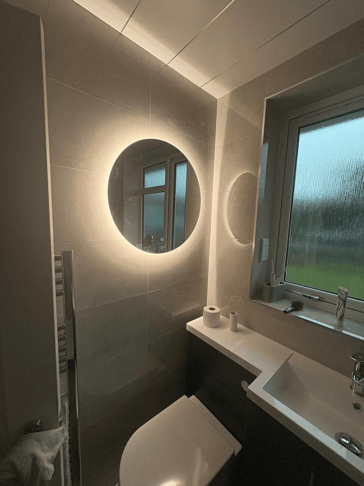 Bathroom with LED backlit round mirror and recessed lighting
