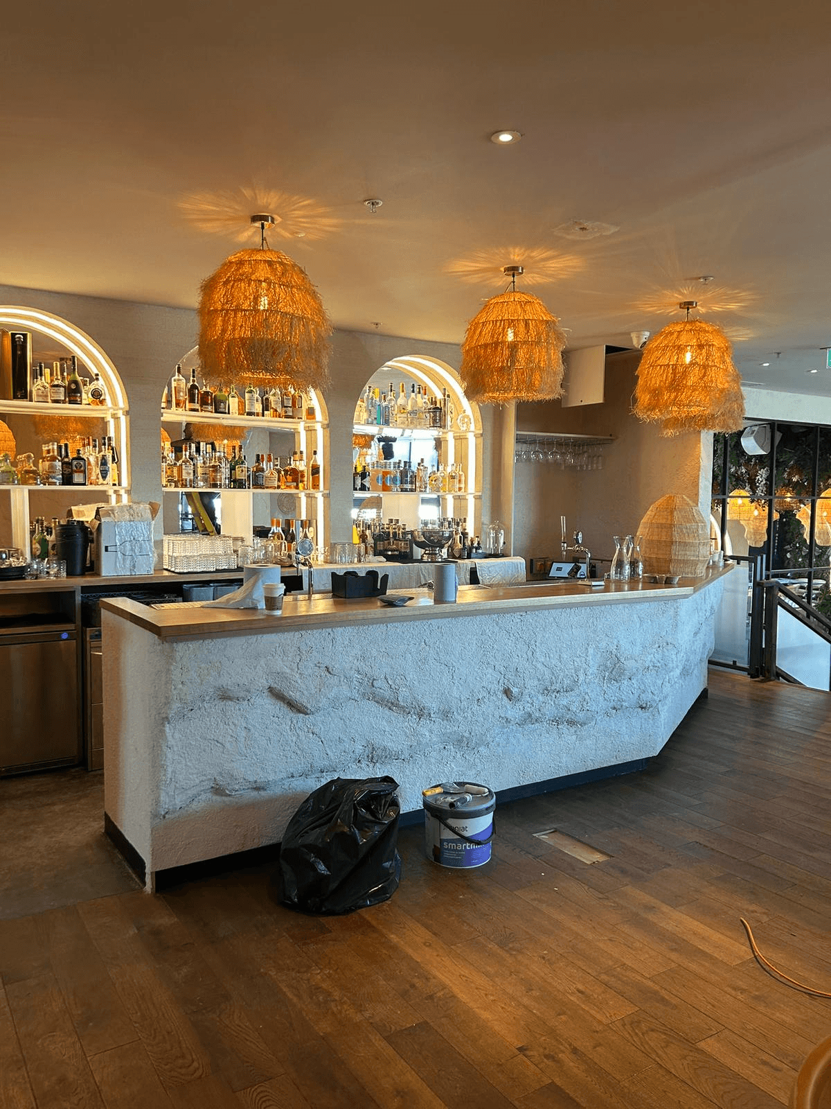 Commercial bar interior with wicker pendant lights and backlit shelving