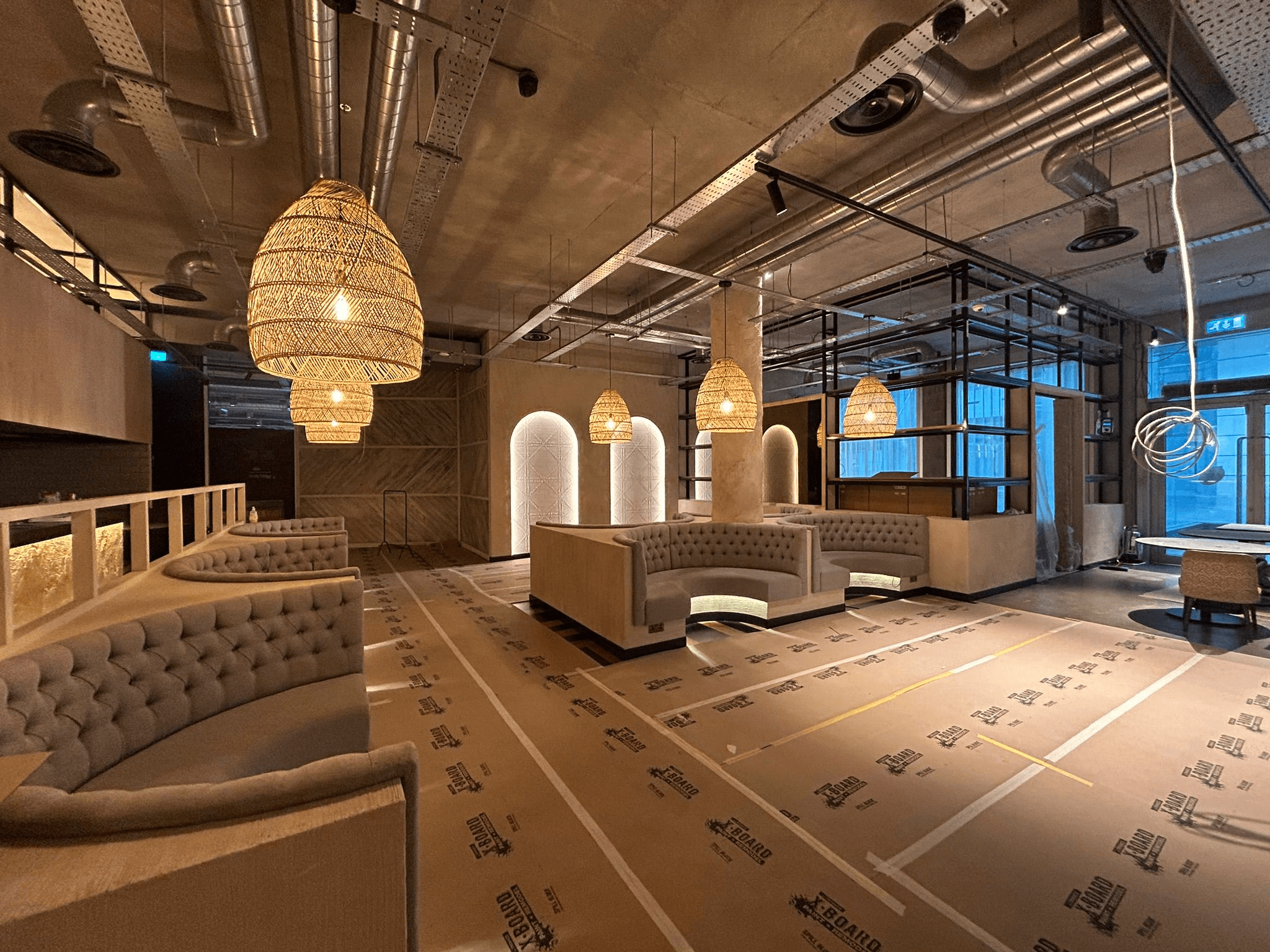 Large commercial lounge bar with wicker pendant lights and illuminated arched alcoves