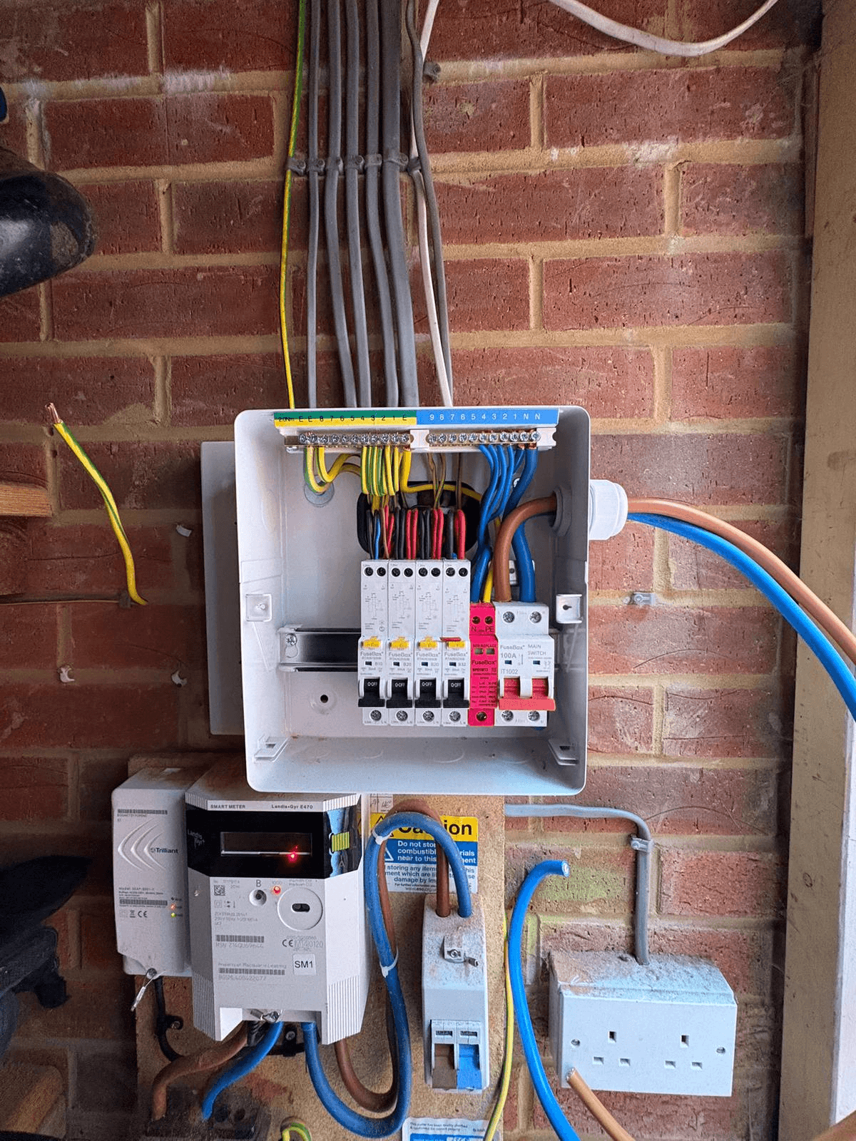 New consumer unit with smart meter and tidy cable management on brick wall