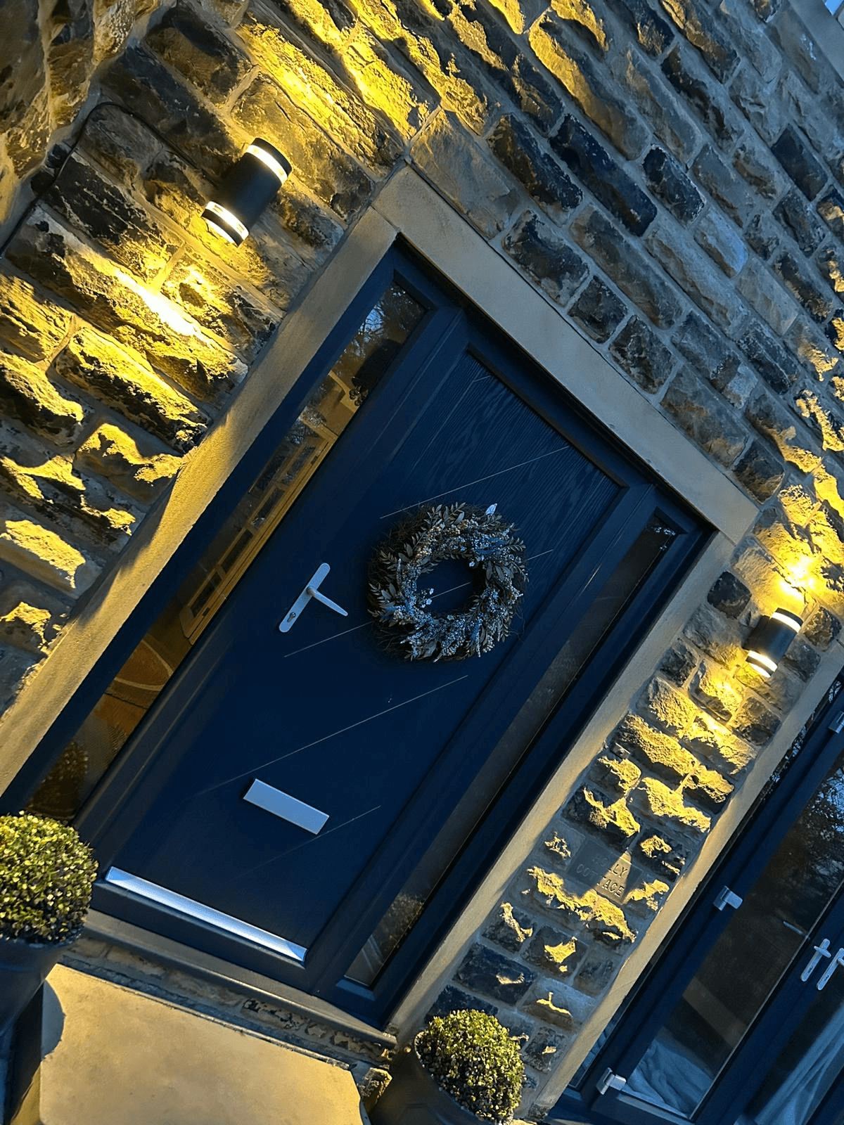 Outdoor front door entrance with warm wall lights on stone building at night