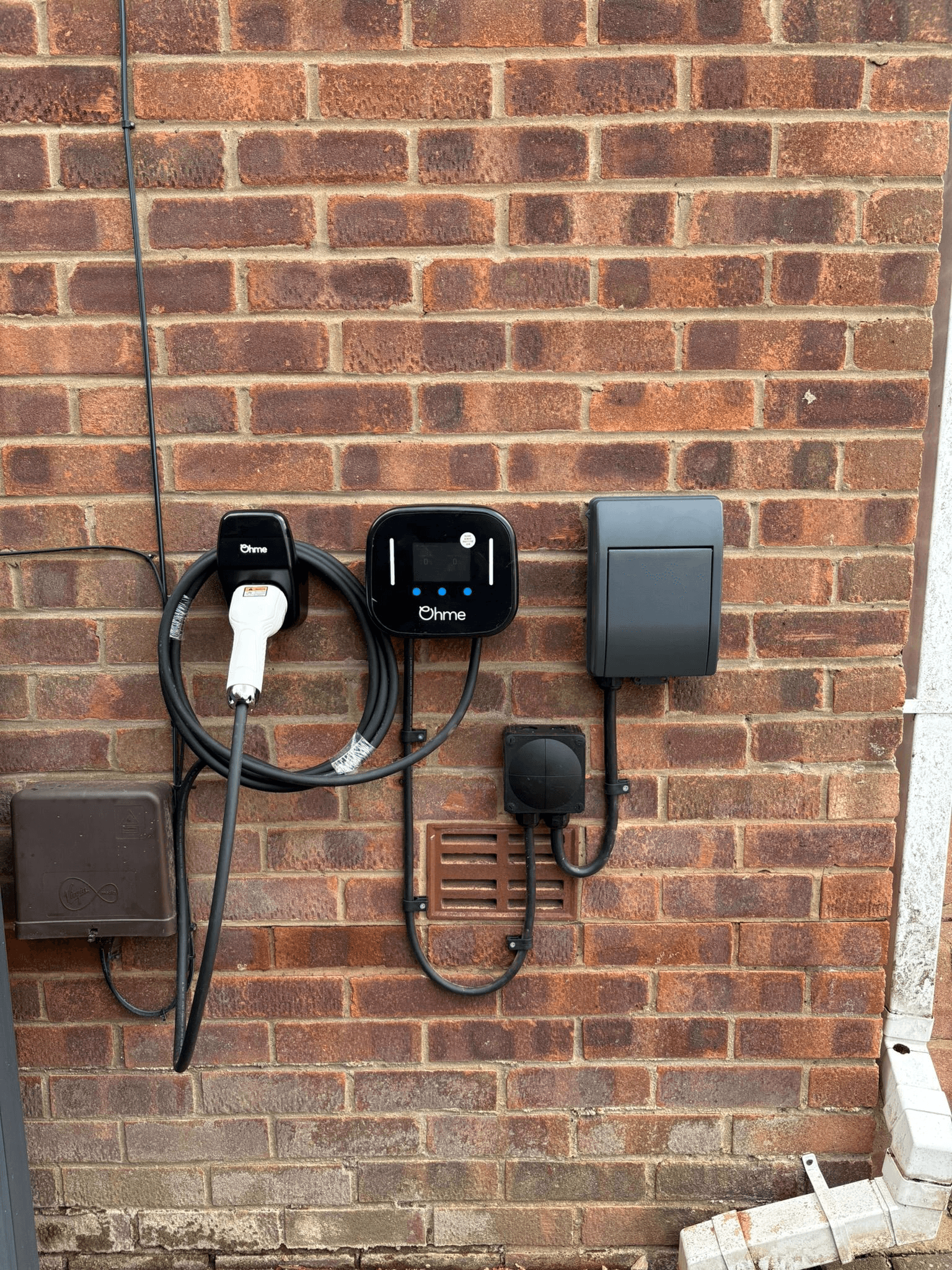 Ohme EV charger installed on exterior brick wall