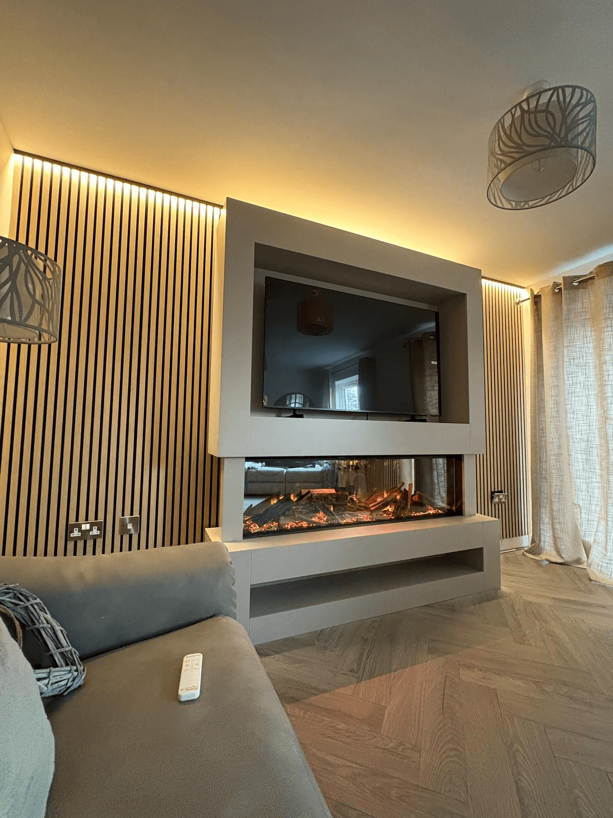 Living room feature wall with LED-lit electric fireplace, TV recess, and ambient strip lighting