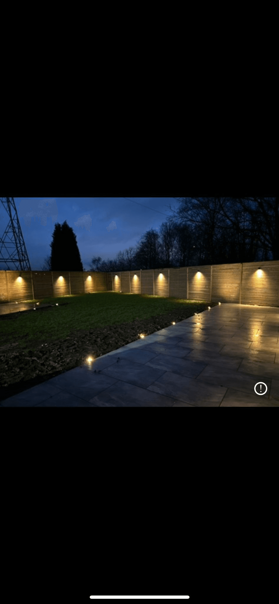 Garden boundary fence with wall uplights and ground-level path lights at night