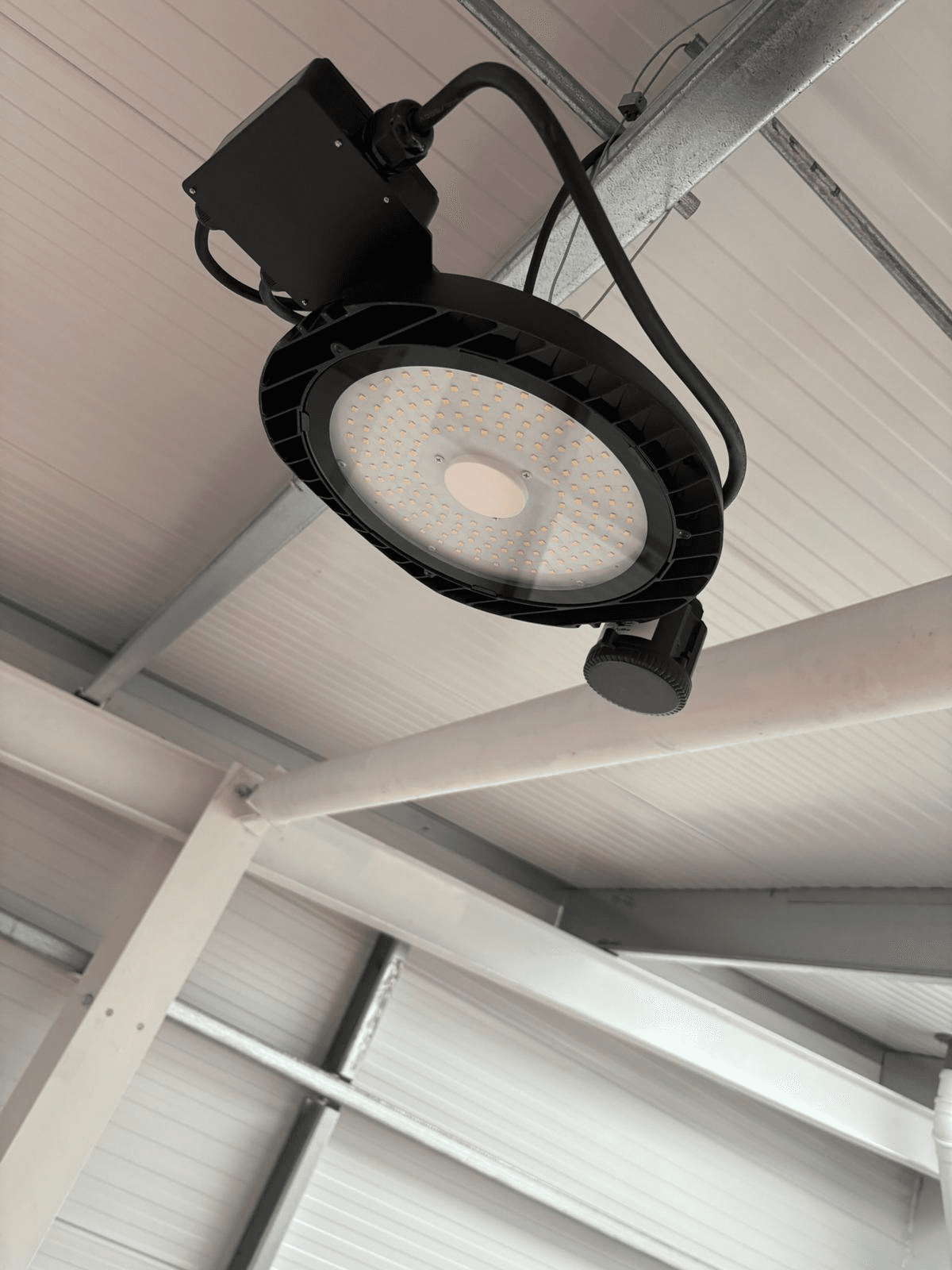Industrial high bay LED light mounted on steel frame in a commercial workshop