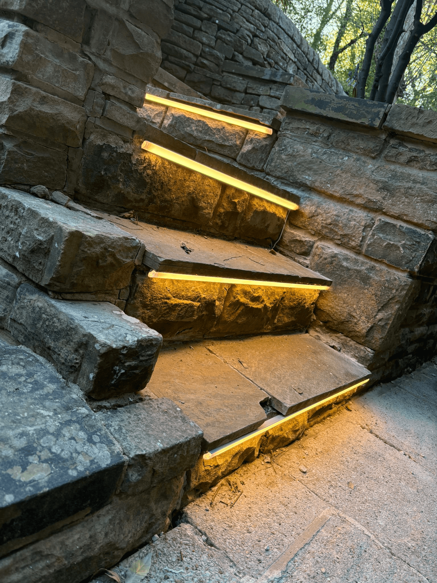 Warm LED strip lights illuminating stone garden steps at dusk