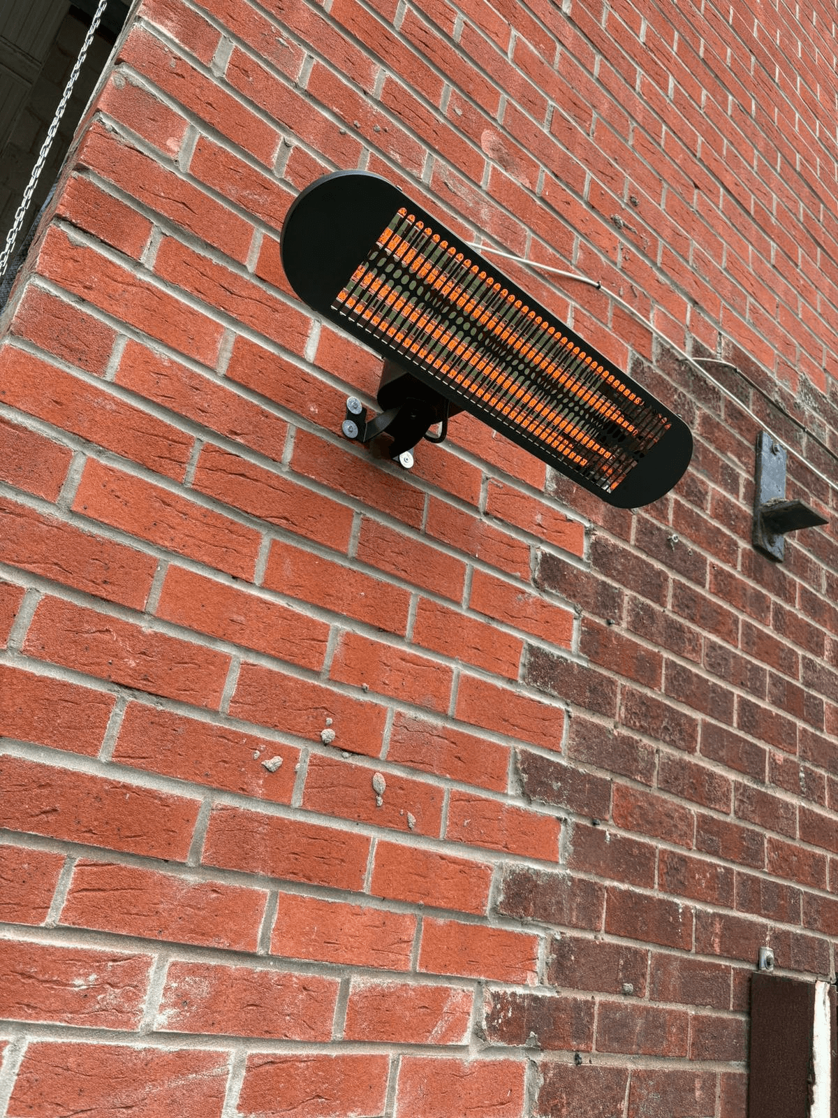 Infrared wall heater mounted on exterior brick wall