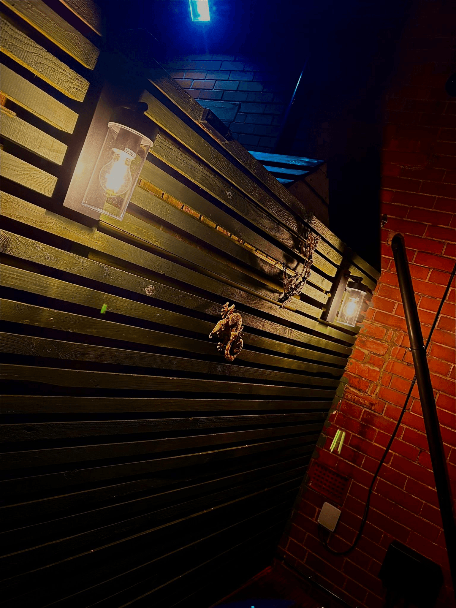 Outdoor wall lantern lights mounted on wooden cladding at night