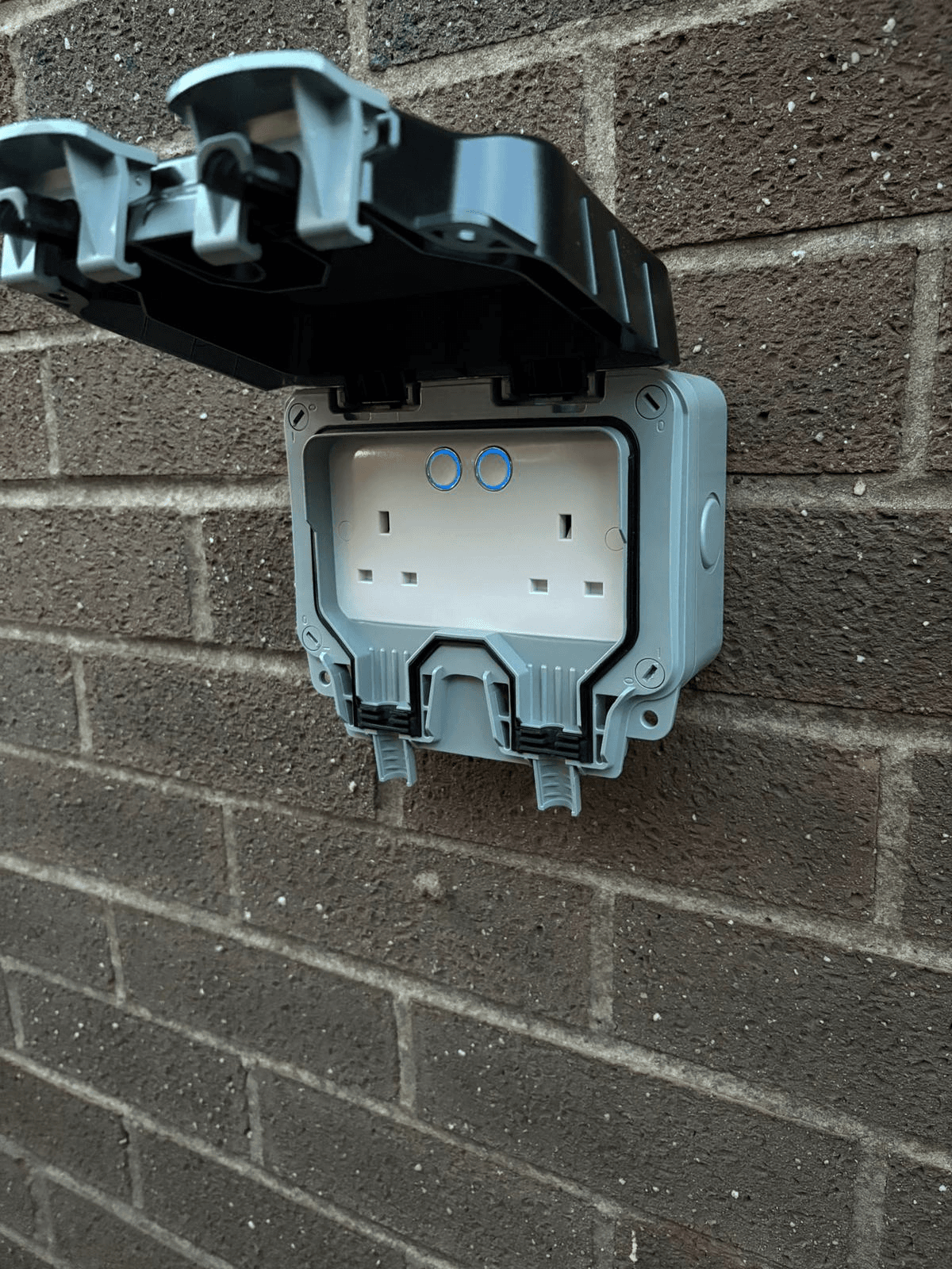 Weatherproof IP65 double socket installed on exterior brick wall